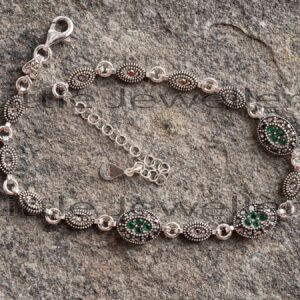 A vintage-style Marcasite bracelet made of pure sterling silver and set with green CZ stones.