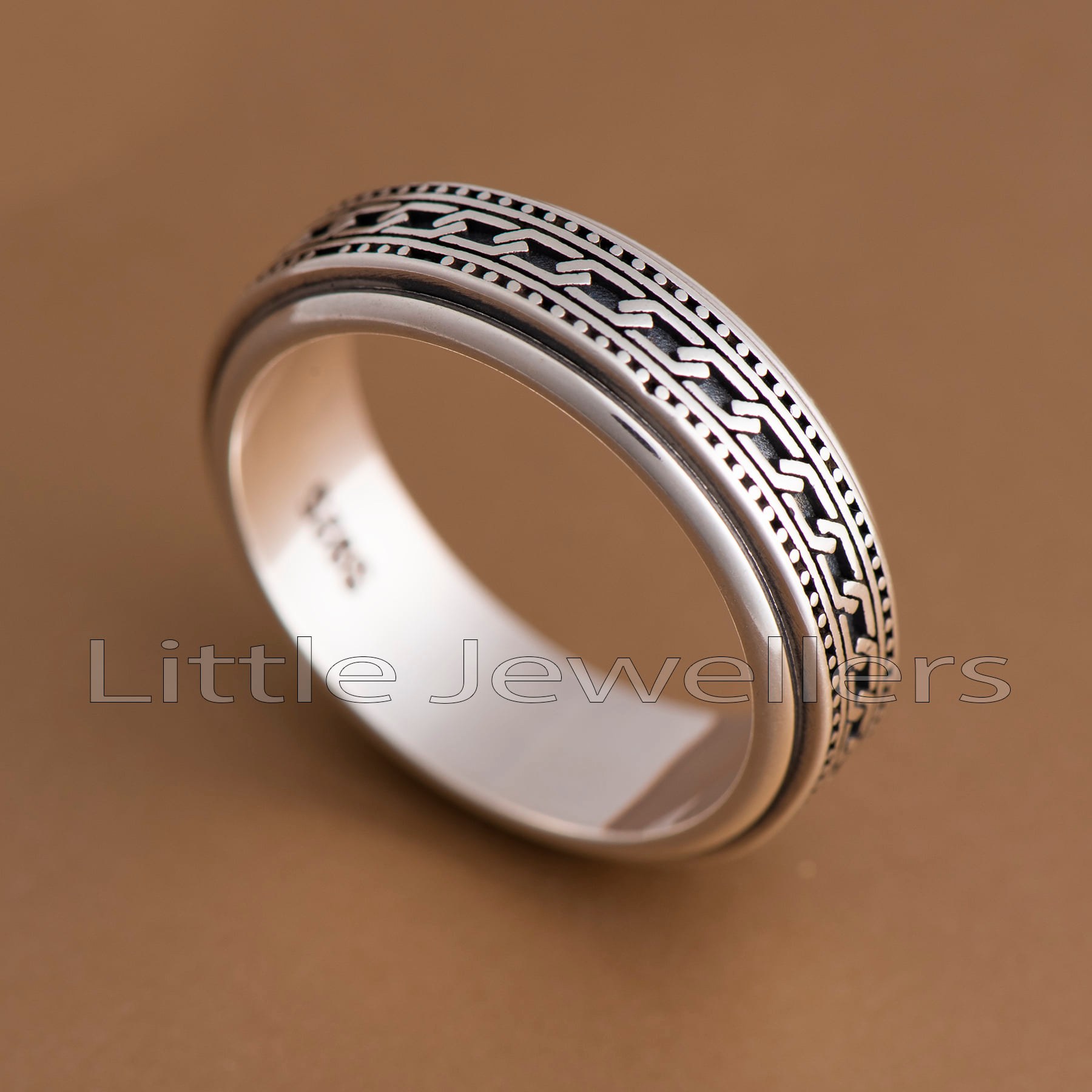 A men's ring featuring a center spinning band. The band features a patterned design in the middle and may spin freely.