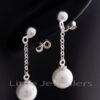 A strand of gleaming pearl earrings connected by a delicate silver thread. Pearls are the birthstone for June.