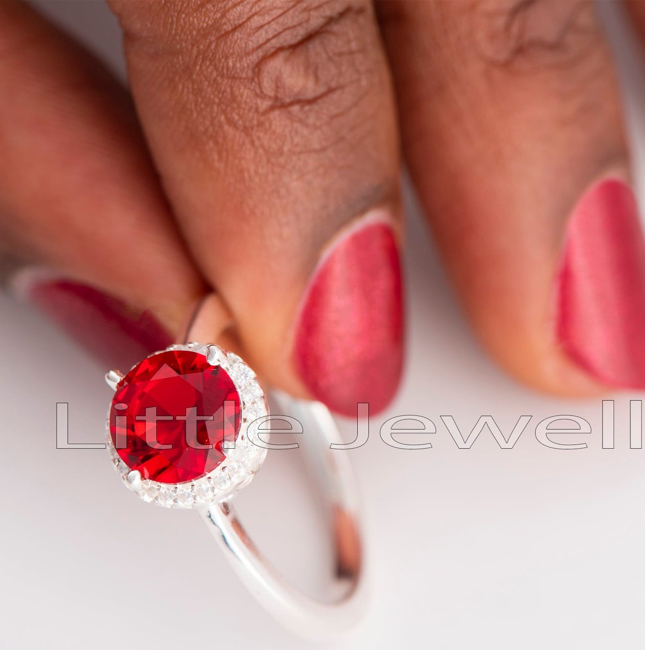 This gleaming Sterling Silver ring has an oval-cut red stone surrounded by a halo of pave cz stones. It will instill confidence