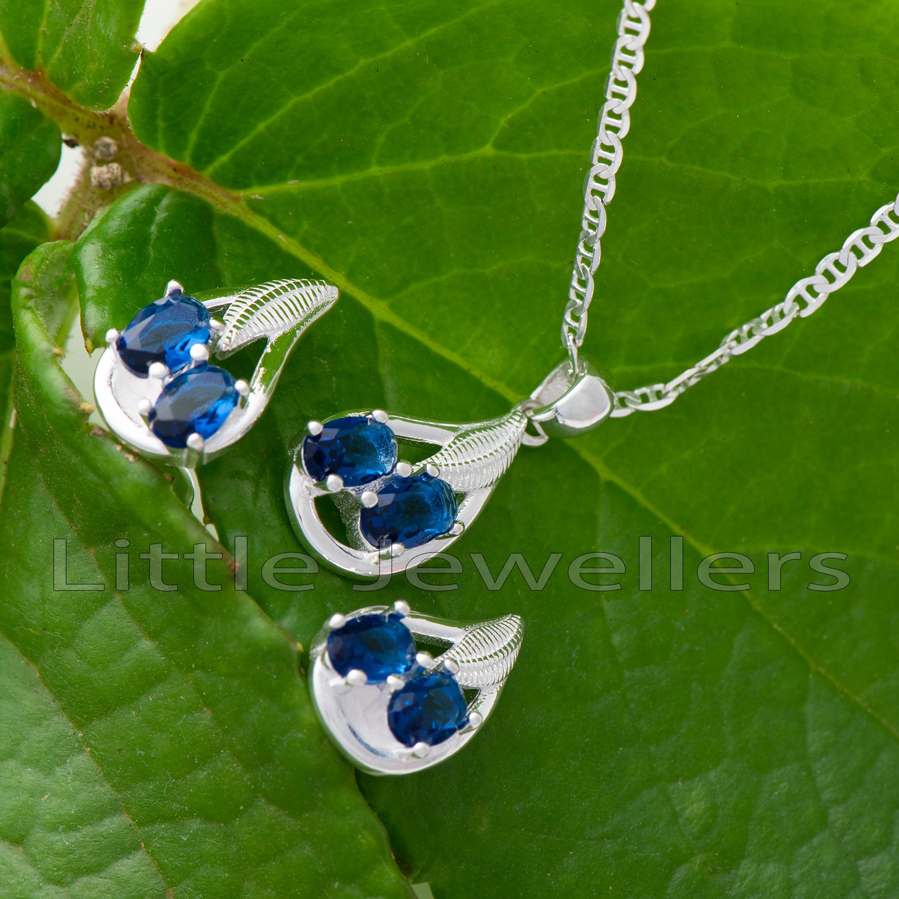 This exquisite piece of jewelry features a magnificent blue gem set in high-quality silver. The gem is flawlessly complemented by a pair of exquisitely crafted earrings and a delicate silver chain.