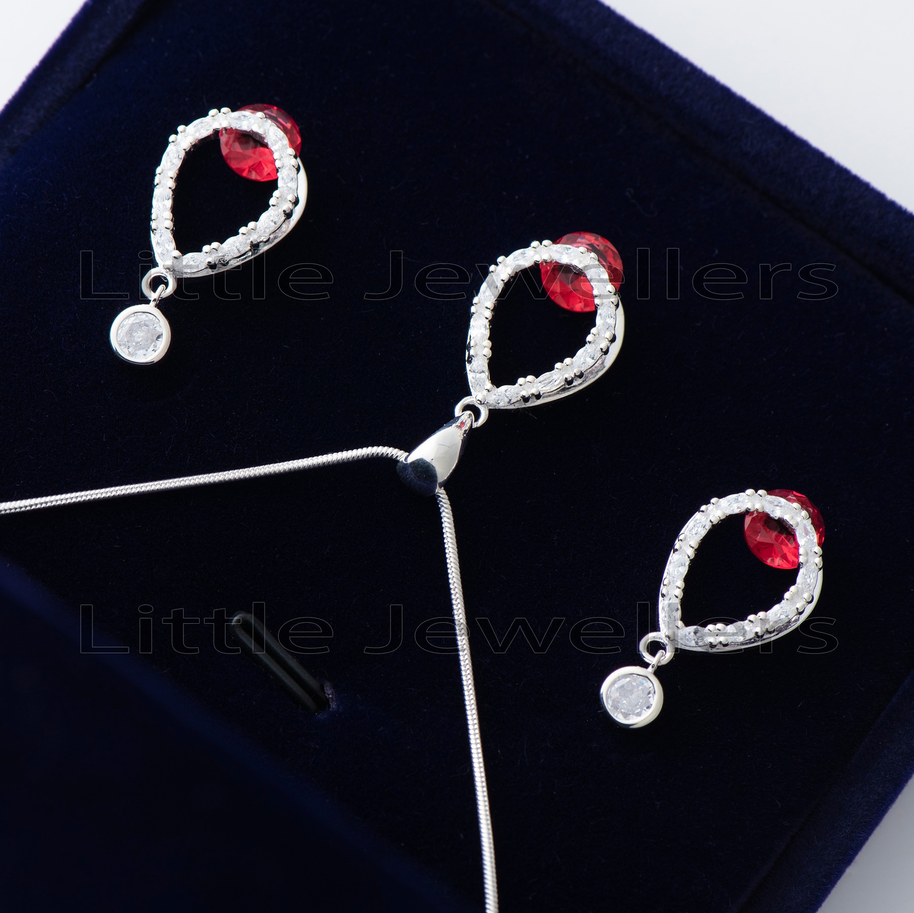 Find the perfect addition to your wardrobe with this stunning silver necklace set. Featuring a shimmering red gem centerpiece & exquisite dangling earrings